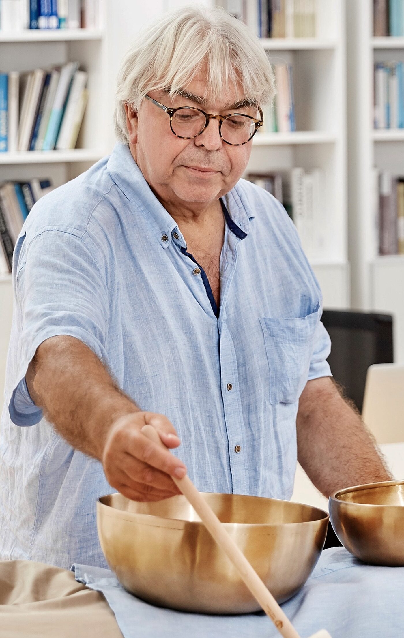 Norbert Kasprowski schlägt am Seminartisch eine große Klangschale mit einem Holzschlägel an.